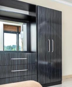 a black dresser with a mirror in a room at Latitudo Suites Uganda in Kajansi +4 photos