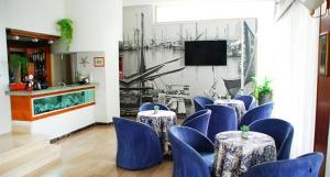 a room with blue chairs and tables and a television at Vibe Hotel in Cattolica