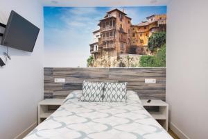 a bedroom with a bed with a painting on the wall at New Hostal Cabañas in Carboneras de Guadazaón