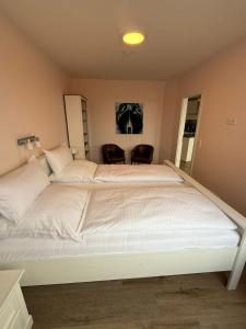 a large white bed in a room with two chairs at Palaceblick in Schleswig