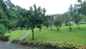 a park with a tree and some flowers and trees at Seasons Inn in Jiaoxi