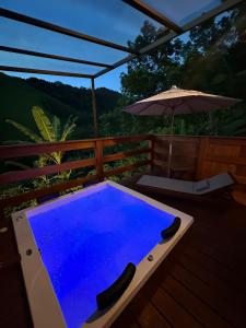 a swimming pool on a deck with an umbrella at Chalés Bermond- Rota da Ferradura in Guarapari