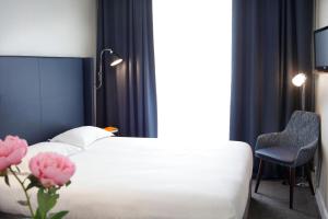 a bedroom with a bed and a chair and pink flowers at Hôtel Londres et New York - Teritoria in Paris