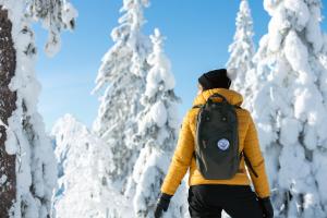 a person with a backpack walking through snow covered trees at Break Sokos Hotel Tahko in Tahkovuori