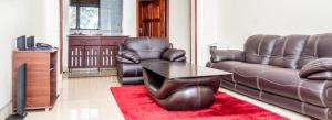 a living room with a leather couch and a table at Latitudo Suites Uganda in Kajansi