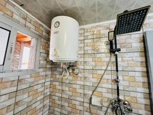 a shower in a bathroom with a tank on the wall at CAMERHOME Lycée Cité des palmiers in Douala