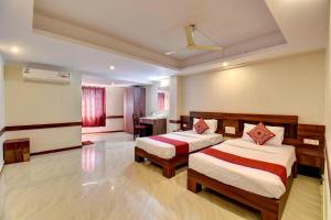 a hotel room with two beds and a table at Sai Arya Residency By The Avyaan in Mangalore
