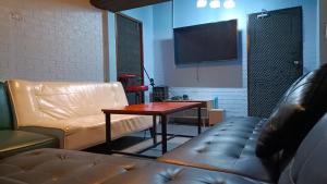 a living room with a couch and a table at บ้านปรินรดา poolvilla สัตหีบ in Sattahip