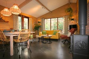 a living room with a fireplace and a table and chairs at De Roek Vakantiebungalows in Otterlo