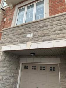 a house with a garage door with the number at Comfortable Room with Free Parking in Brampton