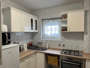 a kitchen with white cabinets and a sink at Monro Apartment in Hévíz