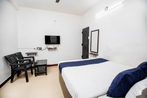 a bedroom with a bed and a desk and a tv at Starlight Hotel1Square in Pondicherry