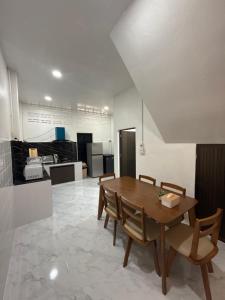 a kitchen and dining room with a wooden table and chairs at O Pha Suk House in Hat Yai