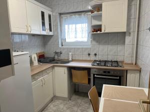 a kitchen with white cabinets and a stove top oven at Monro Apartment in Hévíz +3 photos