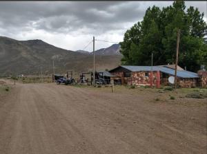 a dirt road in front of a building with a car parked in front at Refugio Los Molles hostal in Las Lenas
