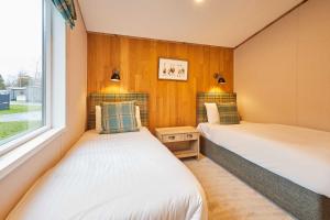 two beds in a room with a window at Sandy Lane 18 - Lodge with Hot Tub in Allerthorpe