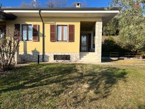 a yellow house with brown shutters and a yard at Villa Cà Bottura agli ulivi in Bardolino