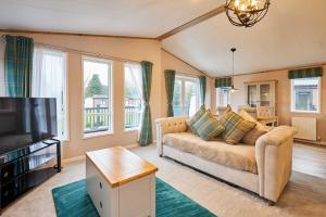 a living room with a couch and a tv at Sandy Lane 18 - Lodge with Hot Tub in Allerthorpe