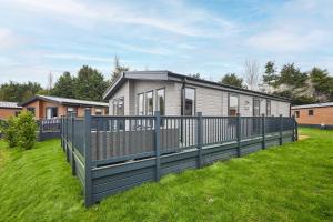 a house with a fence in a yard at Sandy Lane 18 - Lodge with Hot Tub in Allerthorpe