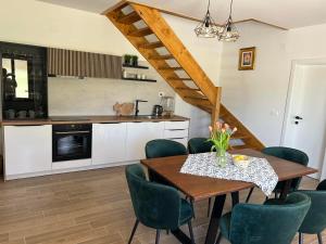 a kitchen with a wooden table and green chairs at Villa BELEVITA odmor u prirodi sa grijanim bazenom in Čepelovac