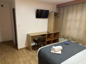 a room with a bed and a desk and a television at Hôtel Le Prince, Poitiers Gare in Poitiers