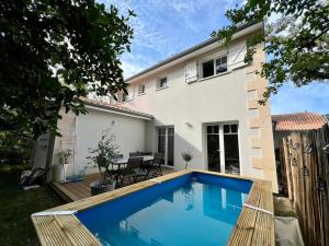 a swimming pool in front of a house at Villa Petit Caprice - Piscine privée au calme dans jardin arboré in Lanton