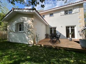 a wooden deck in front of a white house at Villa Petit Caprice - Piscine privée au calme dans jardin arboré in Lanton