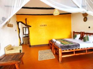 a bedroom with a bed and a bench in a room at Hornbill Bush Lodge in Pakwach East