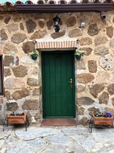 a green door on the side of a stone building at Las Casitas de Layos in Layos