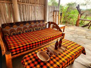 a plaid couch sitting on a porch with a table at Hornbill Bush Lodge in Pakwach East