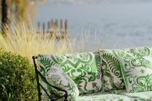 Eine Couch mit Kissen steht neben einem Busch. in der Unterkunft Hotel Eden Roc - The Leading Hotels of the World in Ascona