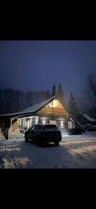 a car parked in front of a house in the snow at Cabana Trofelor in Comandău