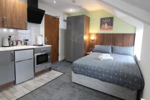 a small bedroom with a bed and a kitchen at Victoria House - Deluxe Studios in Coventry City Centre, free parking, by COVSTAYS in Coventry