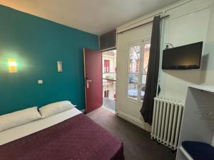 ein Schlafzimmer mit Bett, Fernseher und Fenster in der Unterkunft Hotel Chevallier in Levallois-Perret