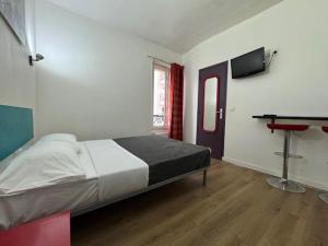 ein Schlafzimmer mit Bett, Tisch und Fernseher in der Unterkunft Hotel Chevallier in Levallois-Perret + 34 Fotos