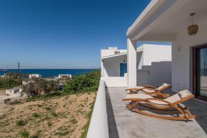 a patio with two chairs and the ocean in the background at Glaucus Summer House sea view in Mandrakia