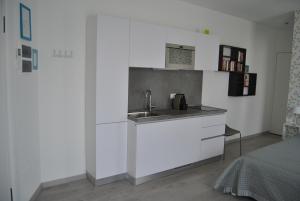 uma cozinha com armários brancos, um lavatório e uma cama em A Zonzo em Vicenza