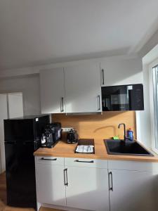a kitchen with white cabinets and a black refrigerator at Cozy downtown studio in Schwäbisch Hall