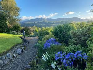 a garden with blue flowers and mountains in the background at Elterwater Park self catering in Ambleside