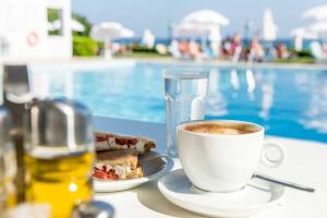 a cup of coffee and a sandwich and a glass of water at Meridien Beach Hotel in Argassi