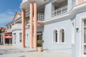 a white house with pink columns at Meridien Beach Hotel in Argassi