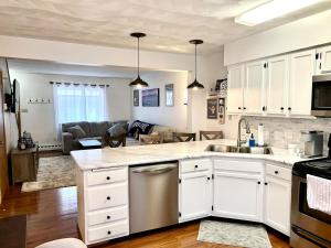 a kitchen with white cabinets and a living room at Alumni Corner in State College