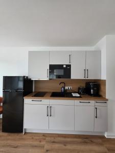 a kitchen with white cabinets and a black refrigerator at Cozy studio in Schwäbisch Hall in Schwäbisch Hall