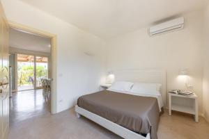 a white bedroom with a bed and a mirror at Cava Li Santi Residence a Santa Caterina in Nardò