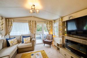 a living room with a couch and a flat screen tv at The Major Oak Lodge with Hot Tub in York