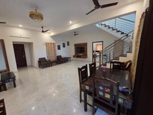 a living room with a table and chairs and a staircase at Bluebell castle in Mahabalipuram