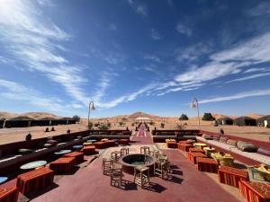 a patio with tables and chairs in the desert at Big Dipper Luxury Camp in Merzouga