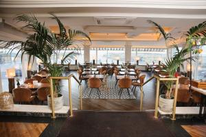 a restaurant with tables and chairs and plants at Hotel Noordzee in Katwijk aan Zee