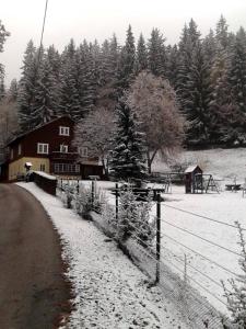 a snow covered field with a house and a fence at Myslivna in Černý Dŭl