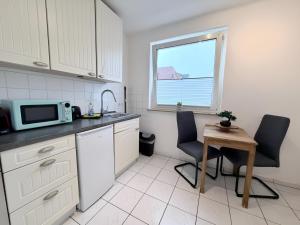 a kitchen with a table and two chairs and a microwave at FeWo Lindenallee Modern & Ruhig in Nordhorn